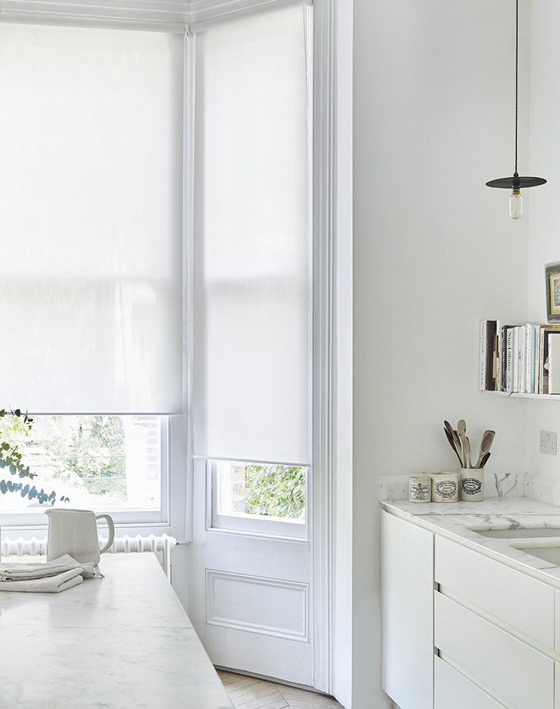 Minimal white kitchen with sleek white roller blinds