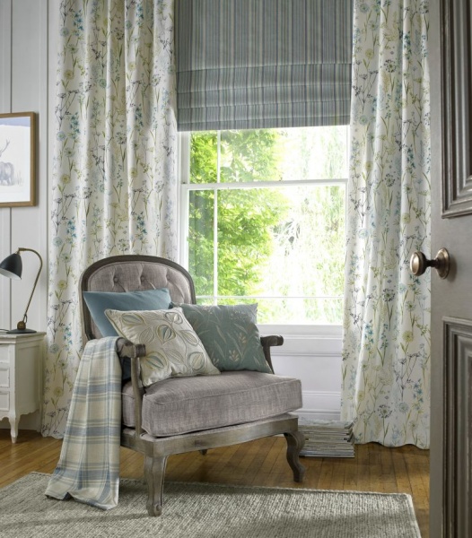 Countryside chic bedroom with floral curtains and striped Roman blinds