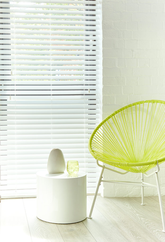 White venetian blinds in room with armchair.