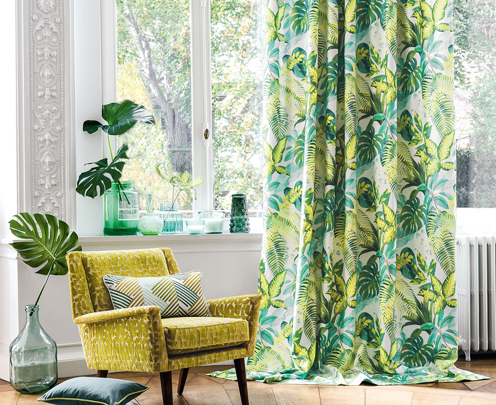 image of living room with yellow chair next to houseplants and floral curtain
