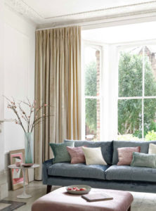 a photo of blue sofa in front of large window with curtains 