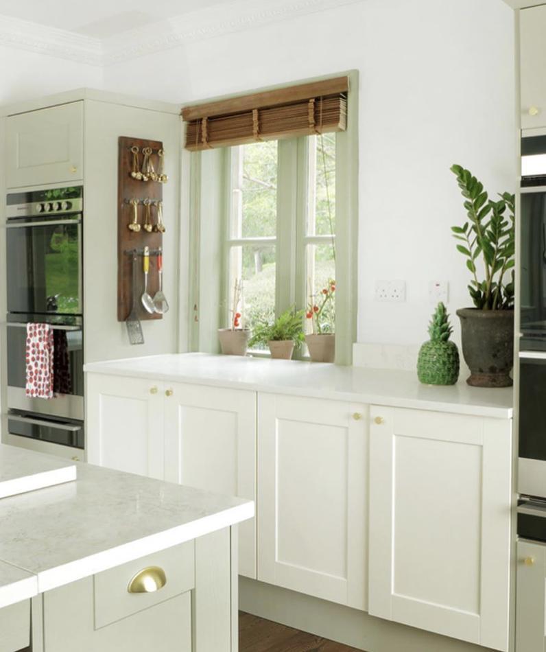 close up photo of kitchen cupboards below window with wooden blind 