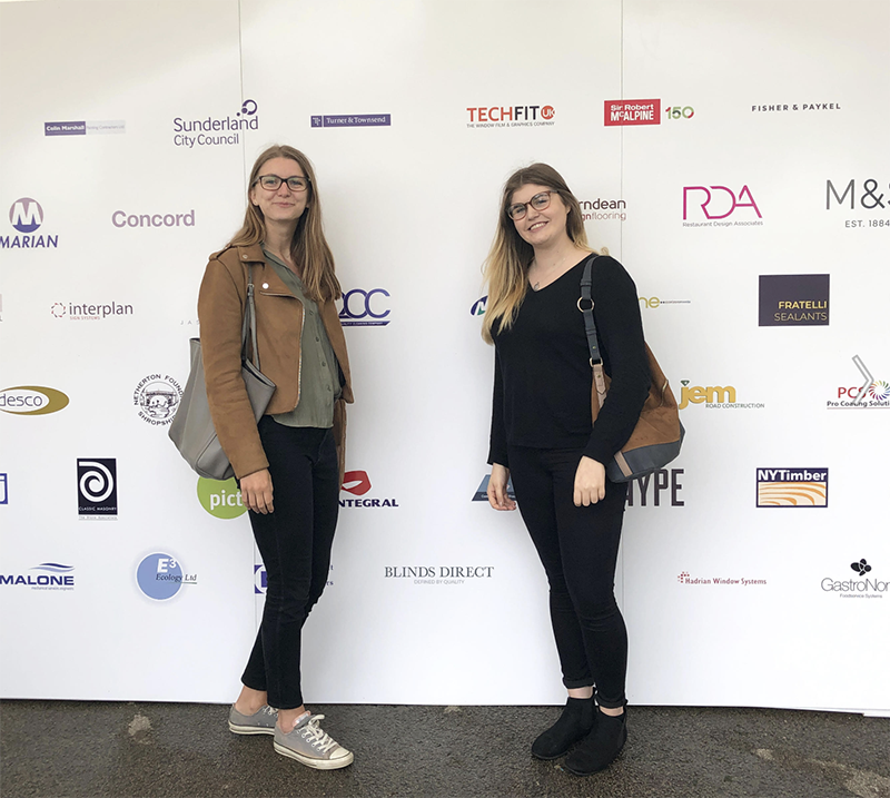 image of two women standing in front of advertising board 