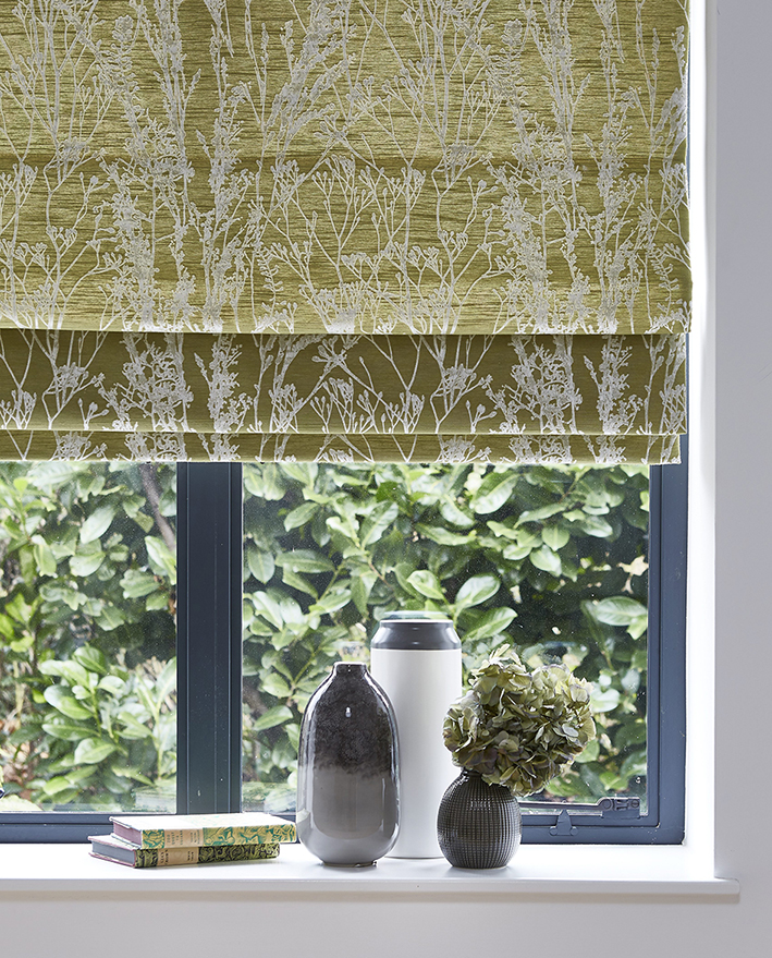 photo of textured roman blind with house plants on the window sill 