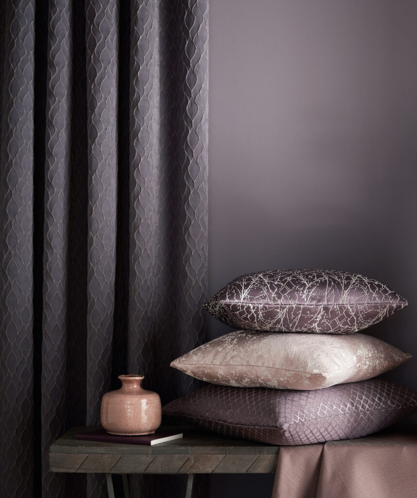 photo stacked cushions next to purple curtains