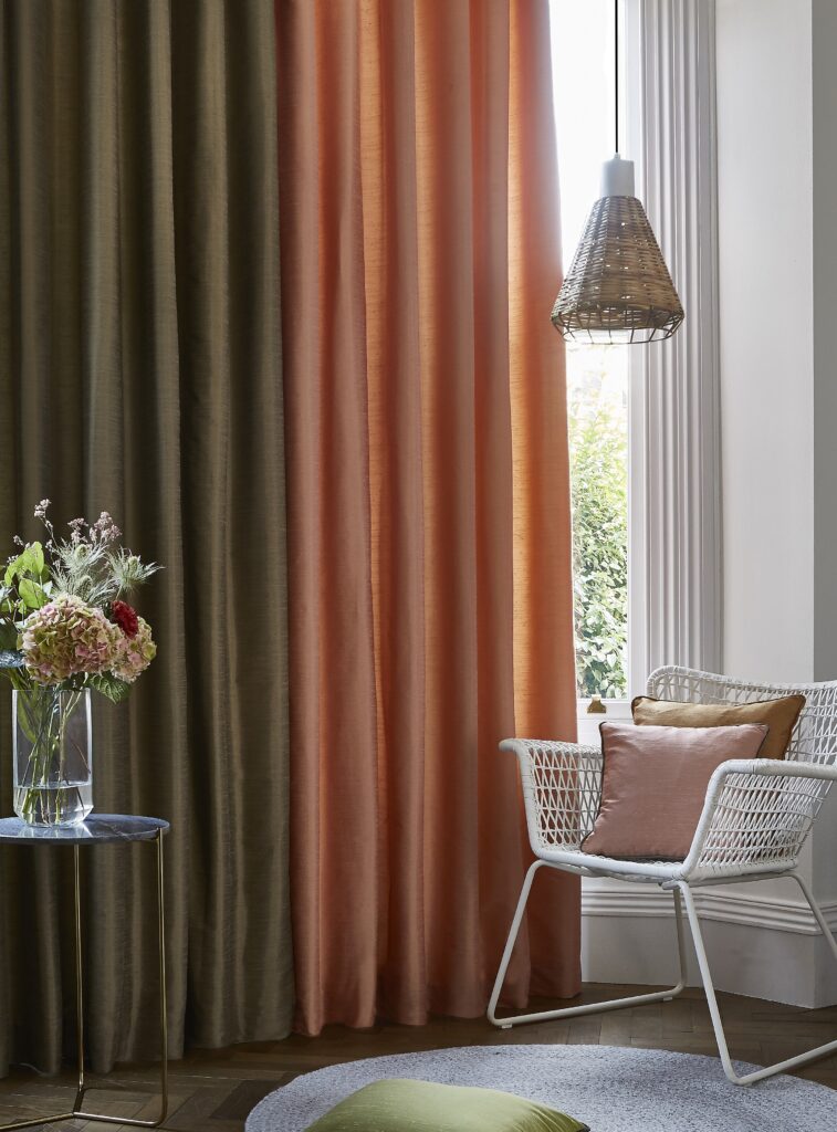 image of living room with white chair next to window with orange and green curtains