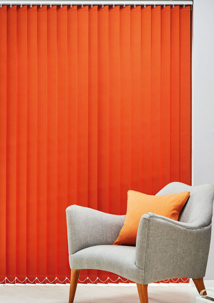 an image to show a chair next to.a window with clean orange vertical blinds