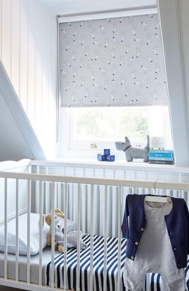 kids room interior layout with white cot, striped blanket and grey roller blind