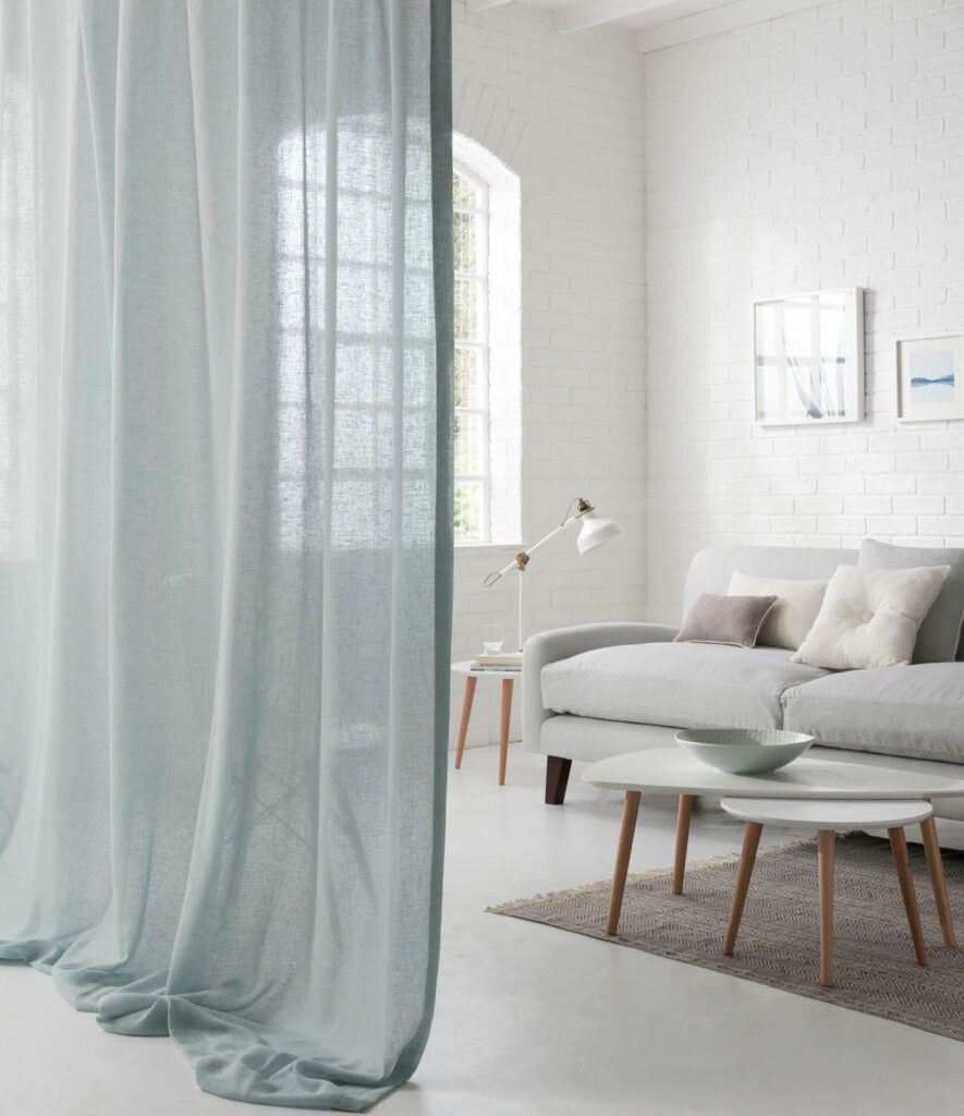 living room with baby blue voile curtain used as a room divider 