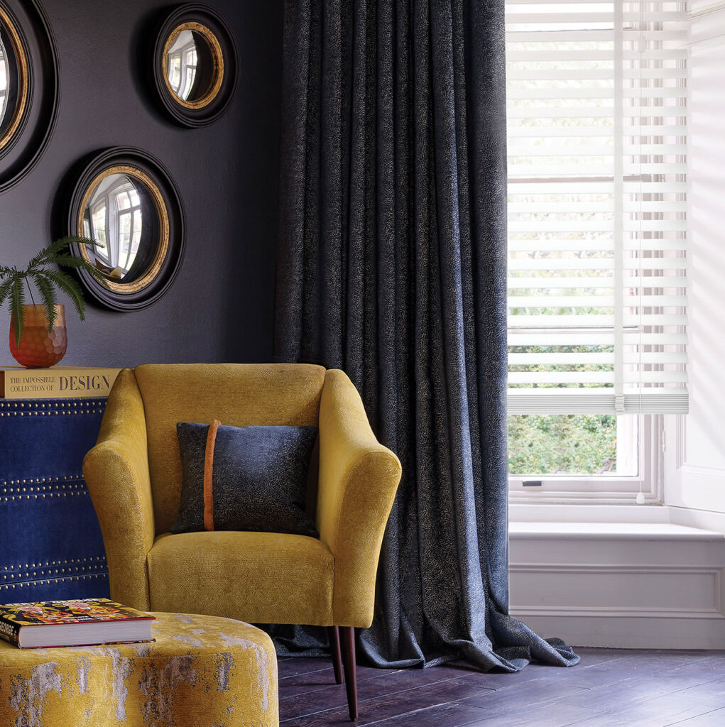 a image of round shaped mirrors on dark blue wall next to yellow chair the show how shapes can help happiness in your home  