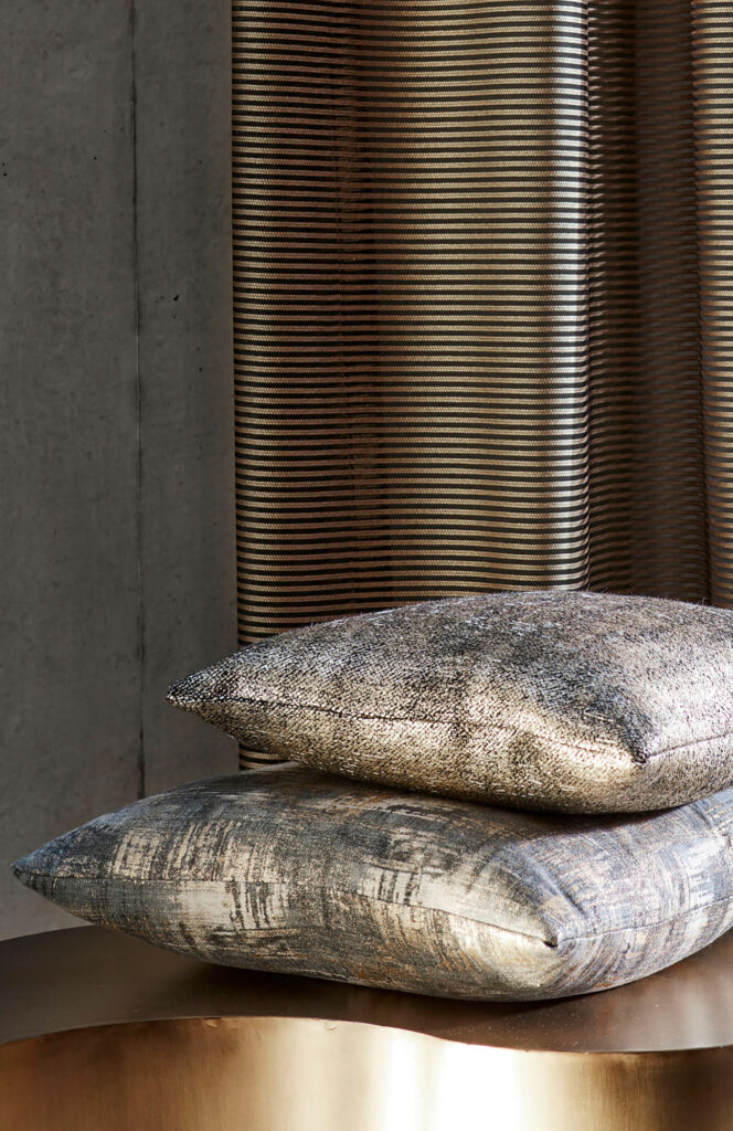 an image of two grey metallic cushions on table next to shiny curtains