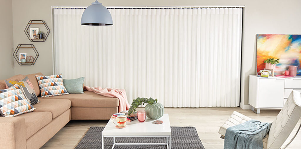 photo of living room with light brown corner sofa, grey rug, white table, house plant and white illusion blinds