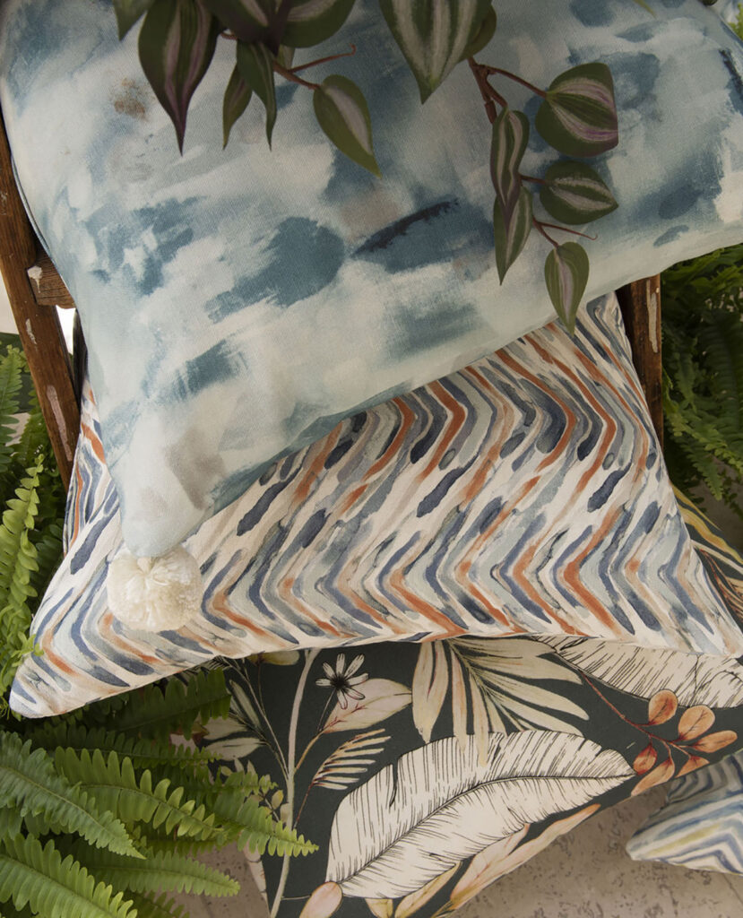 a photo of striped and colourful print cushions next to eucalyptus plant