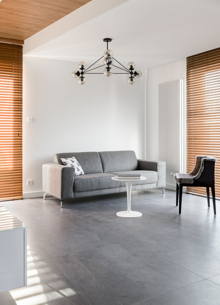 wooden blinds in simple room with grey sofa to show example of minimalist design 