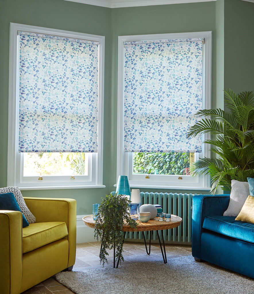 green patterned roller blinds for bay windows in living room setting with green walls and house plants
