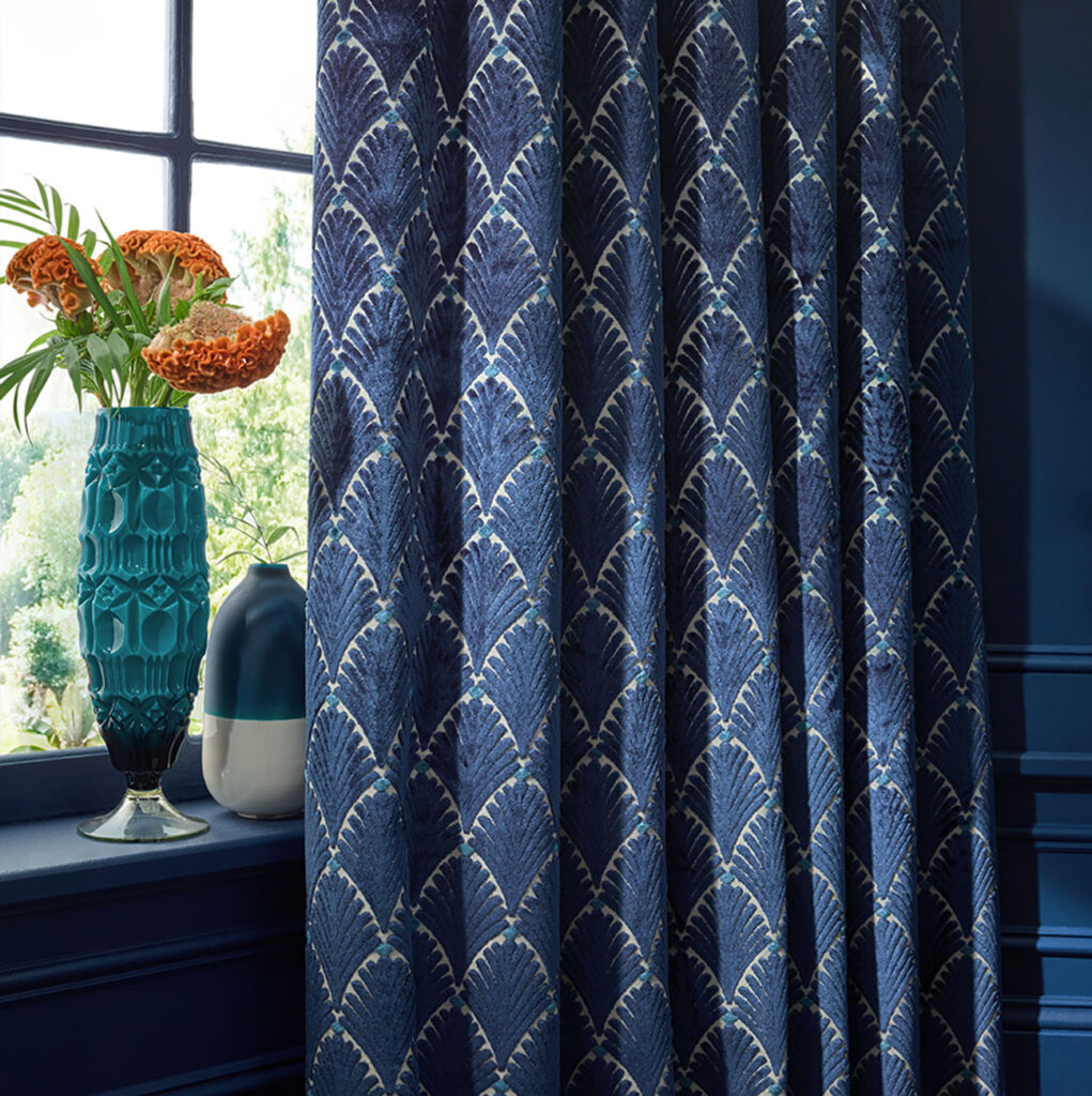 dark blue curtain with seaside fabrics and shells on it next to window with house plant