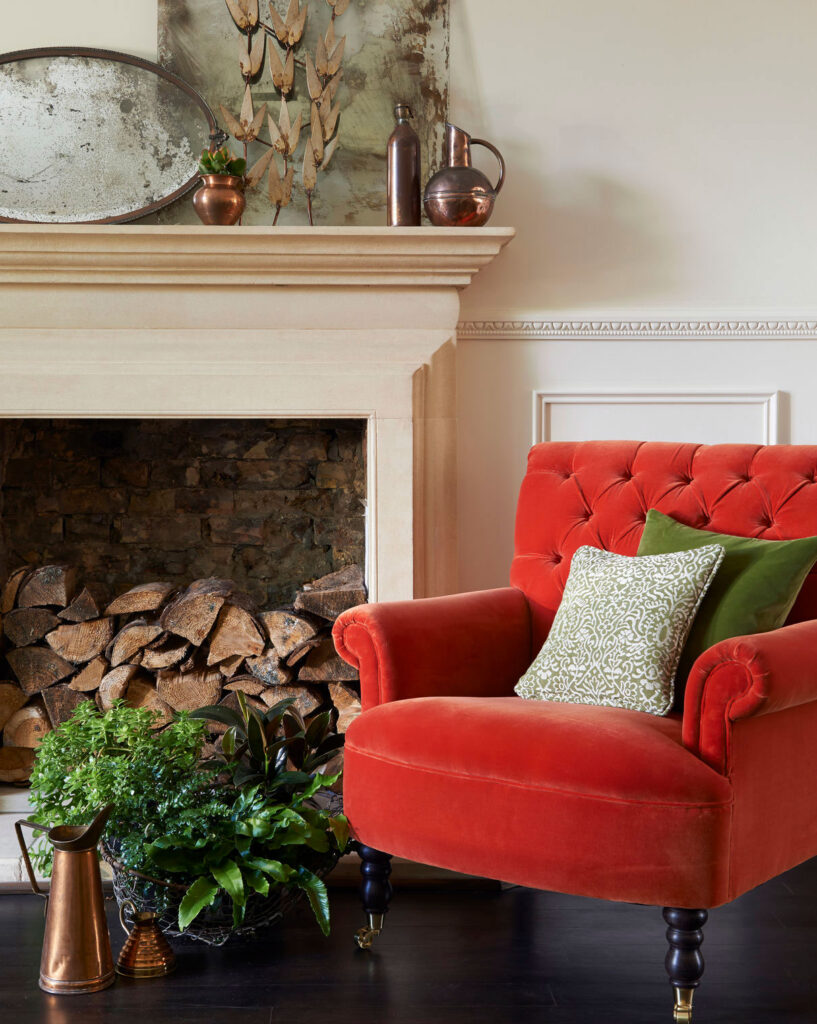 photo of red chair in country cottage next to fireplace to show who interior design can be inspired by the english countryside