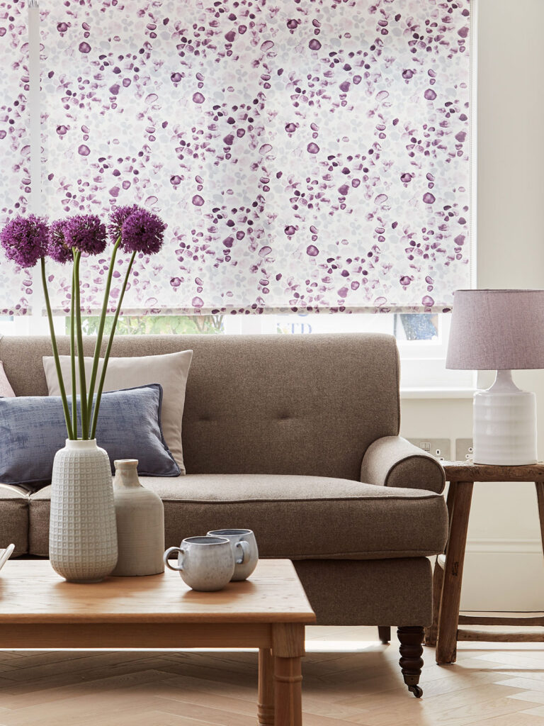 close up image of house flowers on top of table next to window with the colour lilac printed blinds