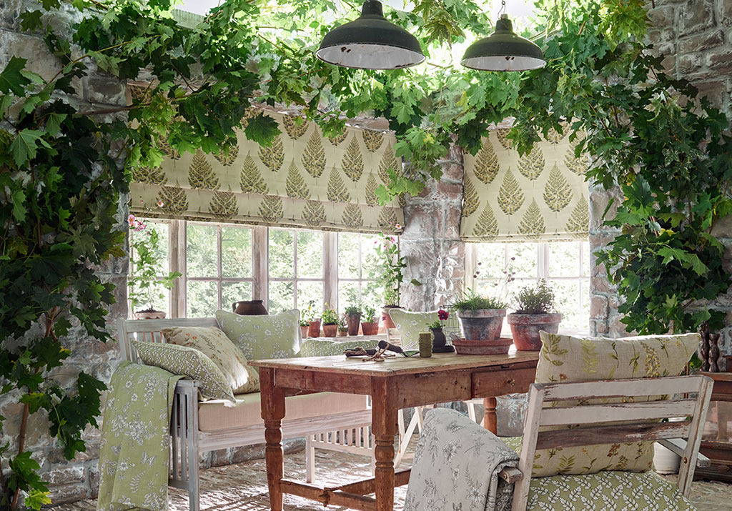 photo of conservatory with lots of house plants and table and chairs next to window