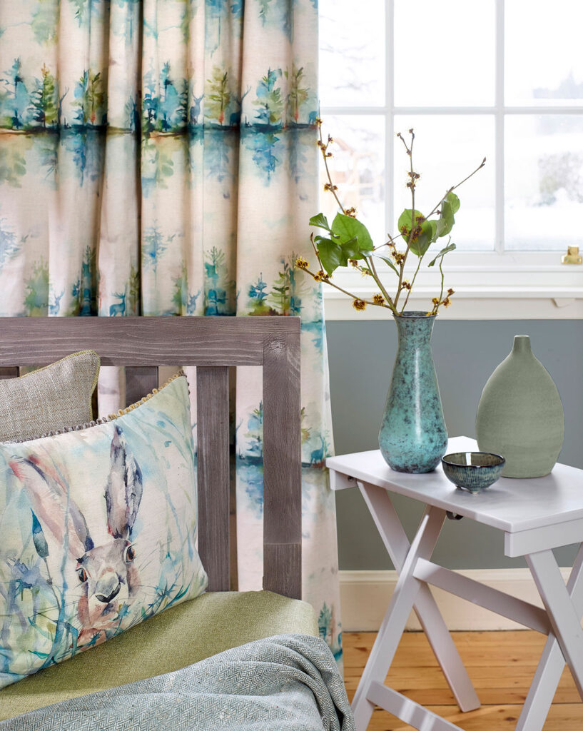 photo of wooden chair with cushion on top next to table with house plant in front window with turquoise curtains