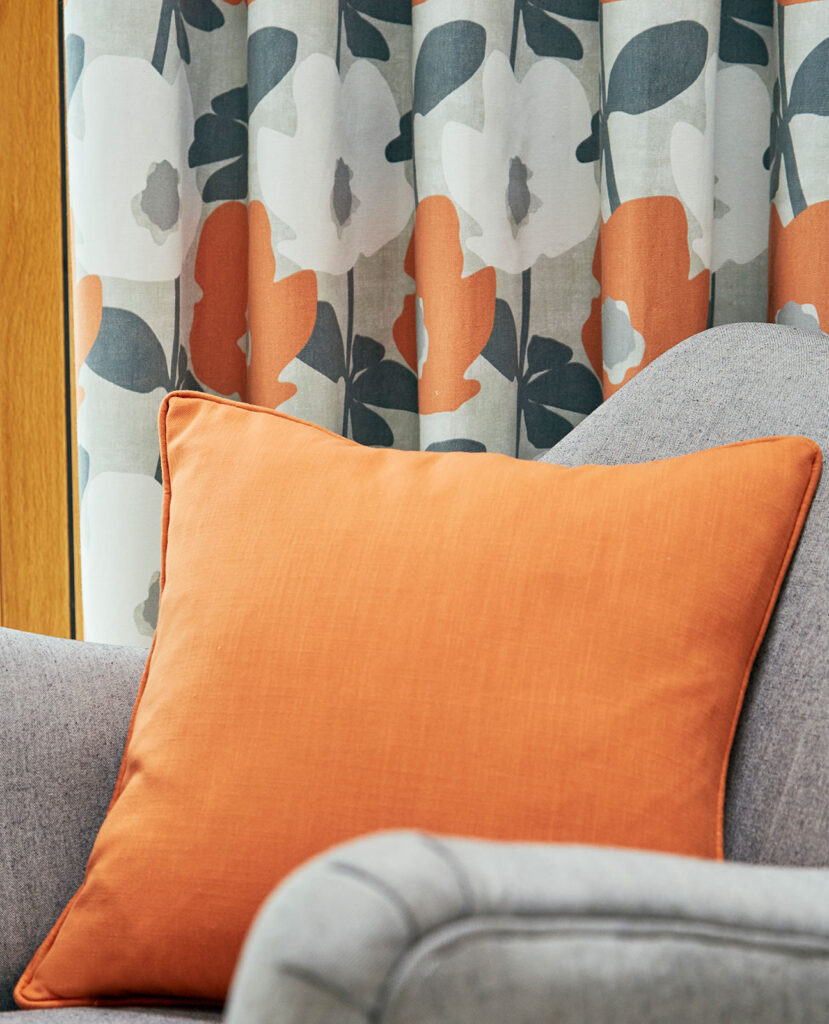 photo of orange cushion on grey sofa to show how to use the grey and orange colour combination in living room 