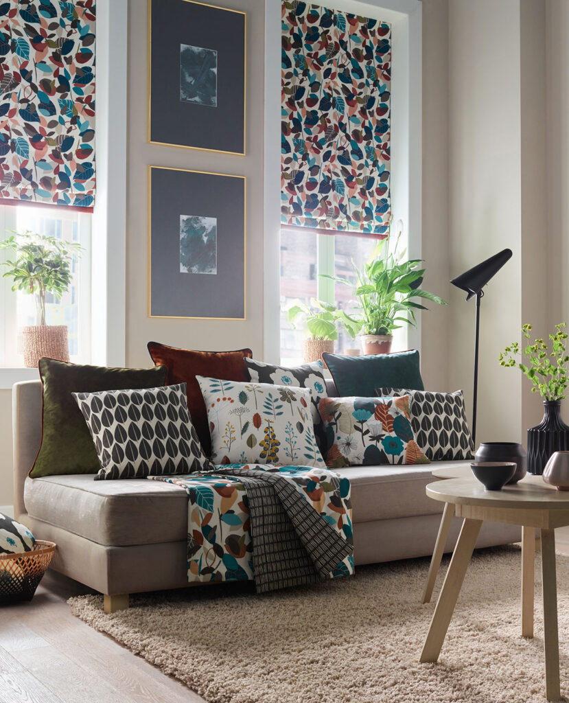 an image of sofa with floral printed cushion next to roller blinds with autumnal print