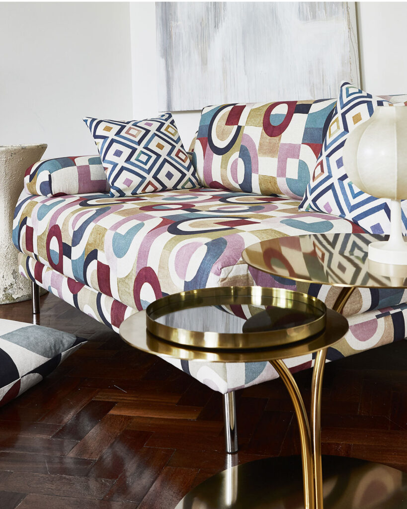 a photo of art deco inspired sofa next to black and gold table