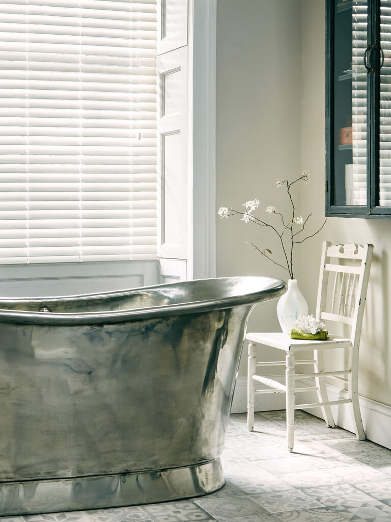 image to show wooden blinds being used in a relaxing bathroom 