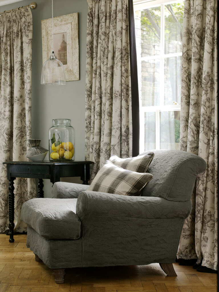 photo showing armchair next to window with soft green coloured curtains 