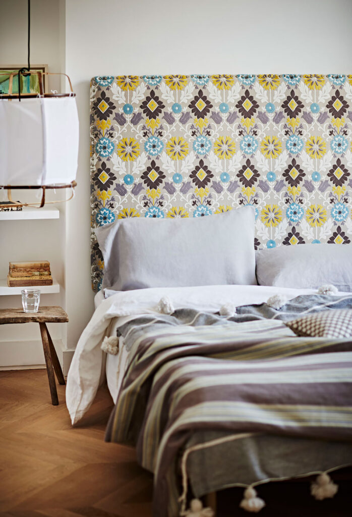 image of bed with floral printed headboard and striped bed linen