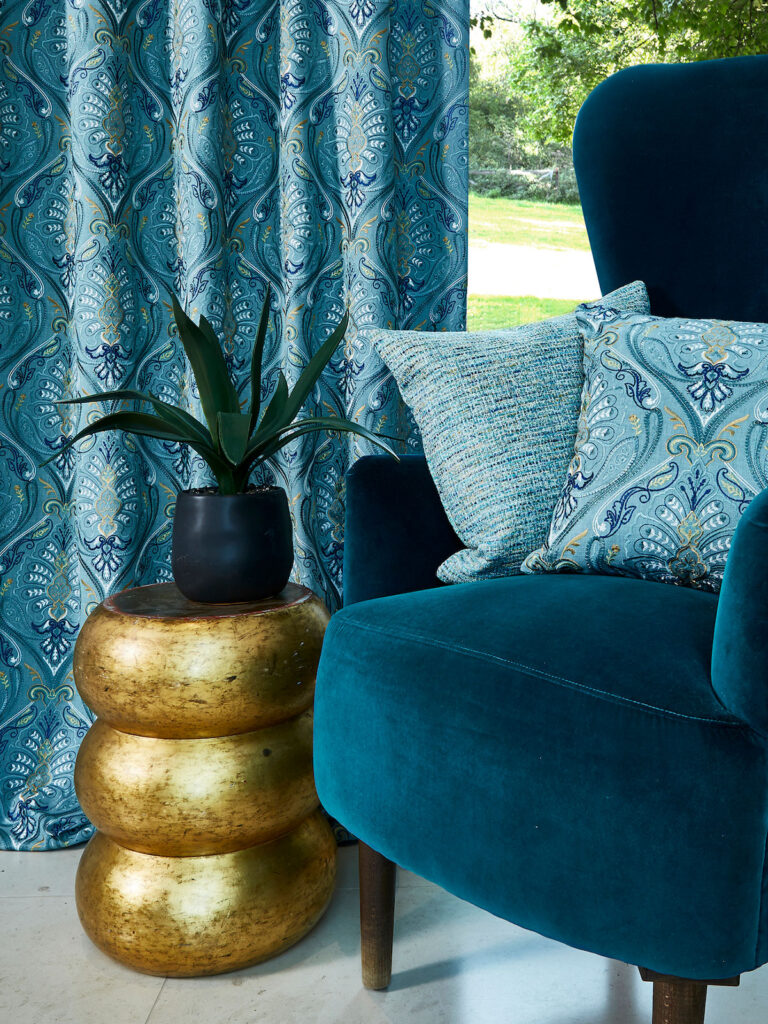 close up image of light blue curtains next to a darker blue chair 
