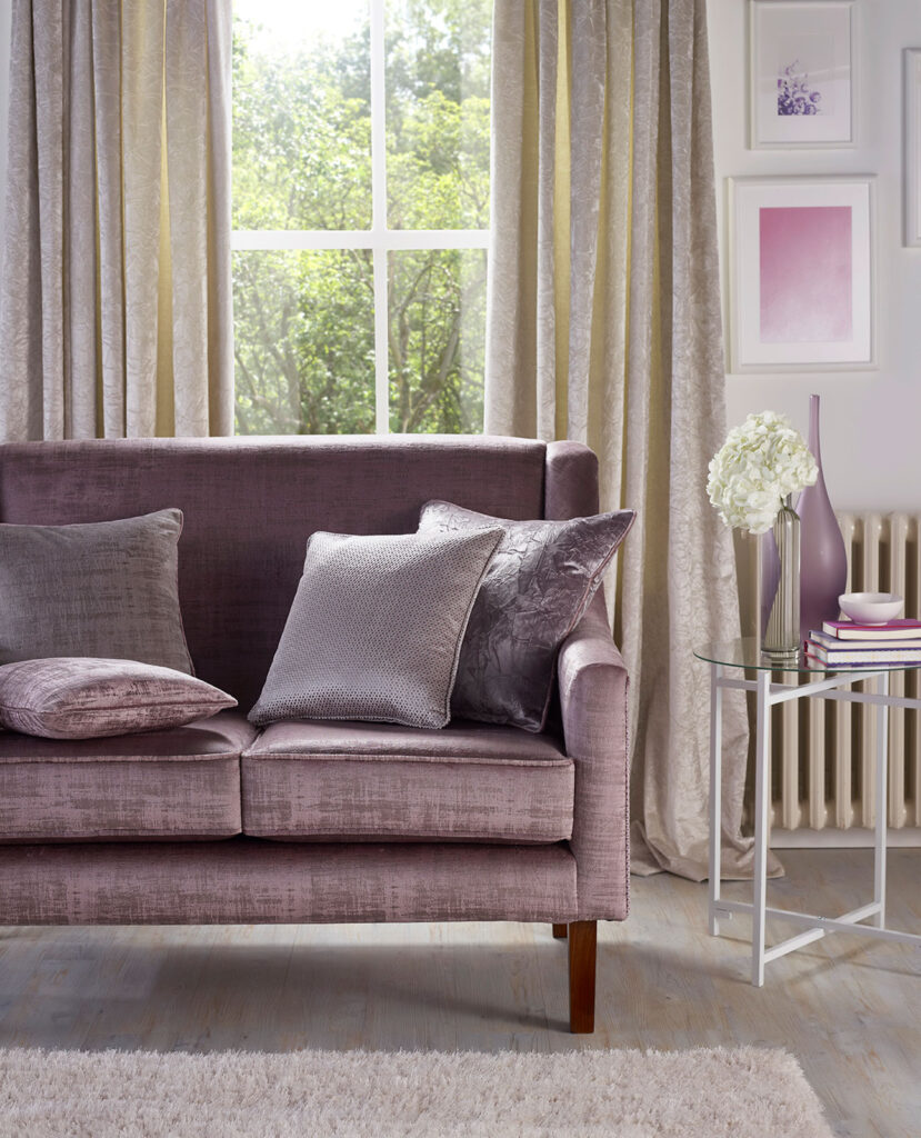 photo of a room using a purple pastel colour palette with a sofa in front of window 