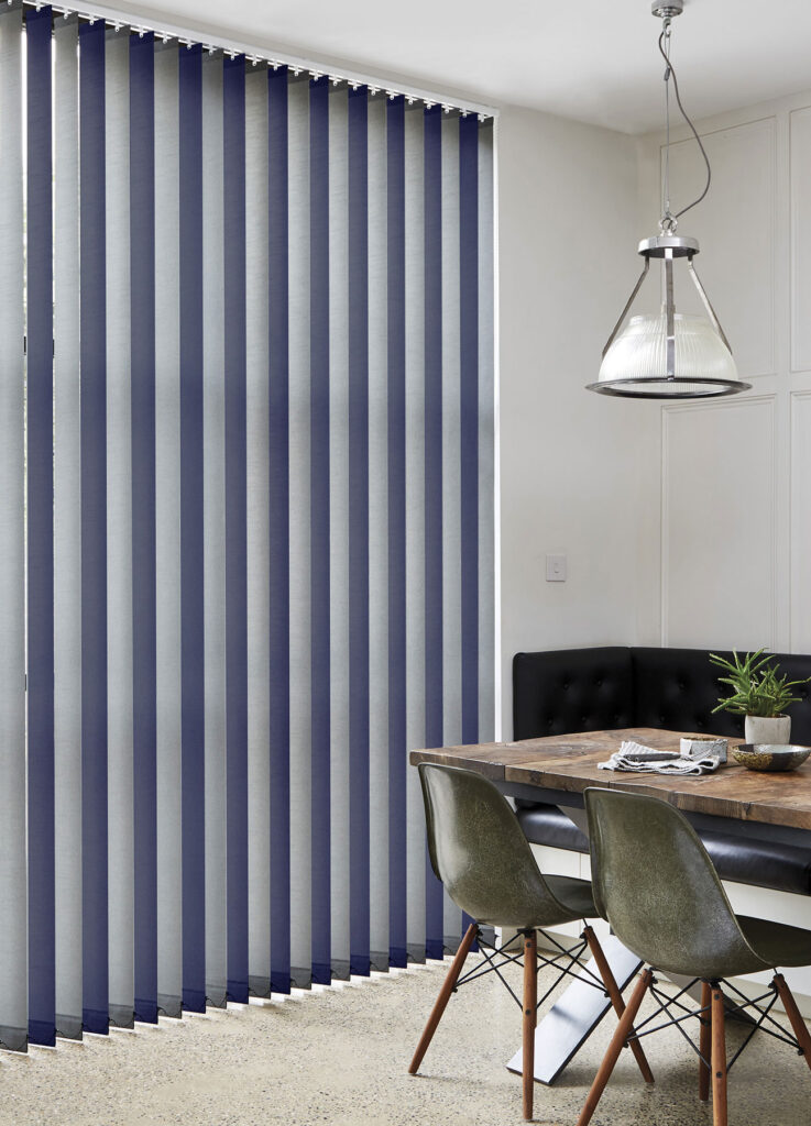 image of dining room table next to patio doors with dark blue and grey alternate vertical blind slats
