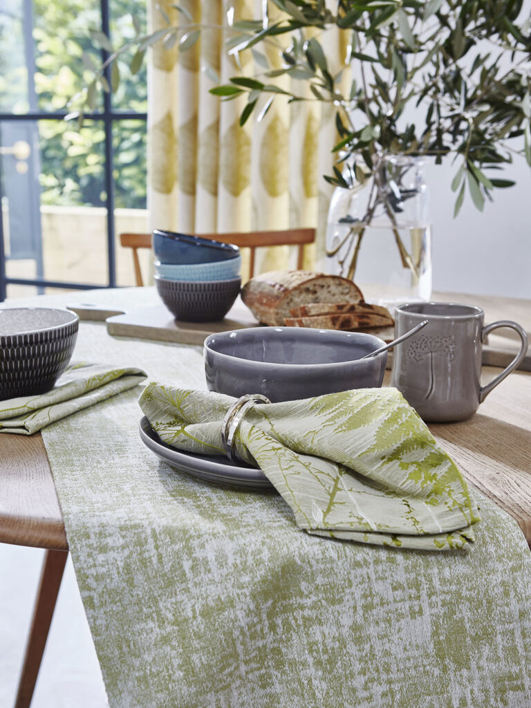 image of kitchen table with sage green coloured cloth on top next to window