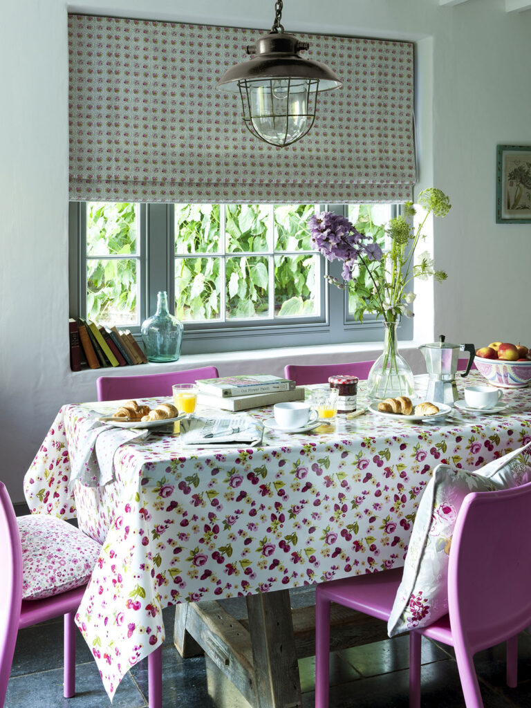 a photo of a kitchen table next to window with pink chairs 