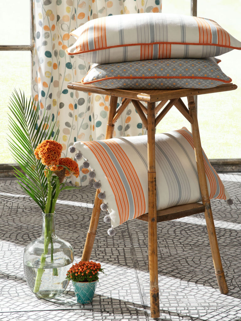 image of three vibrant orange coloured cushions on a stool 