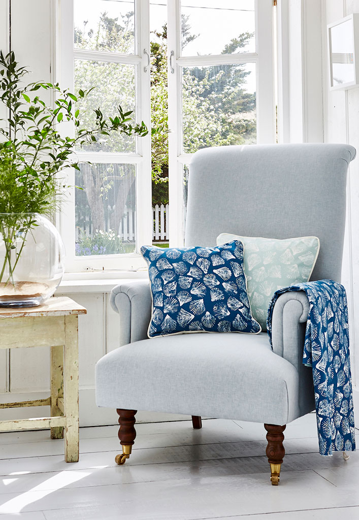 close up image of chair next to open window with coastal design cushion on it