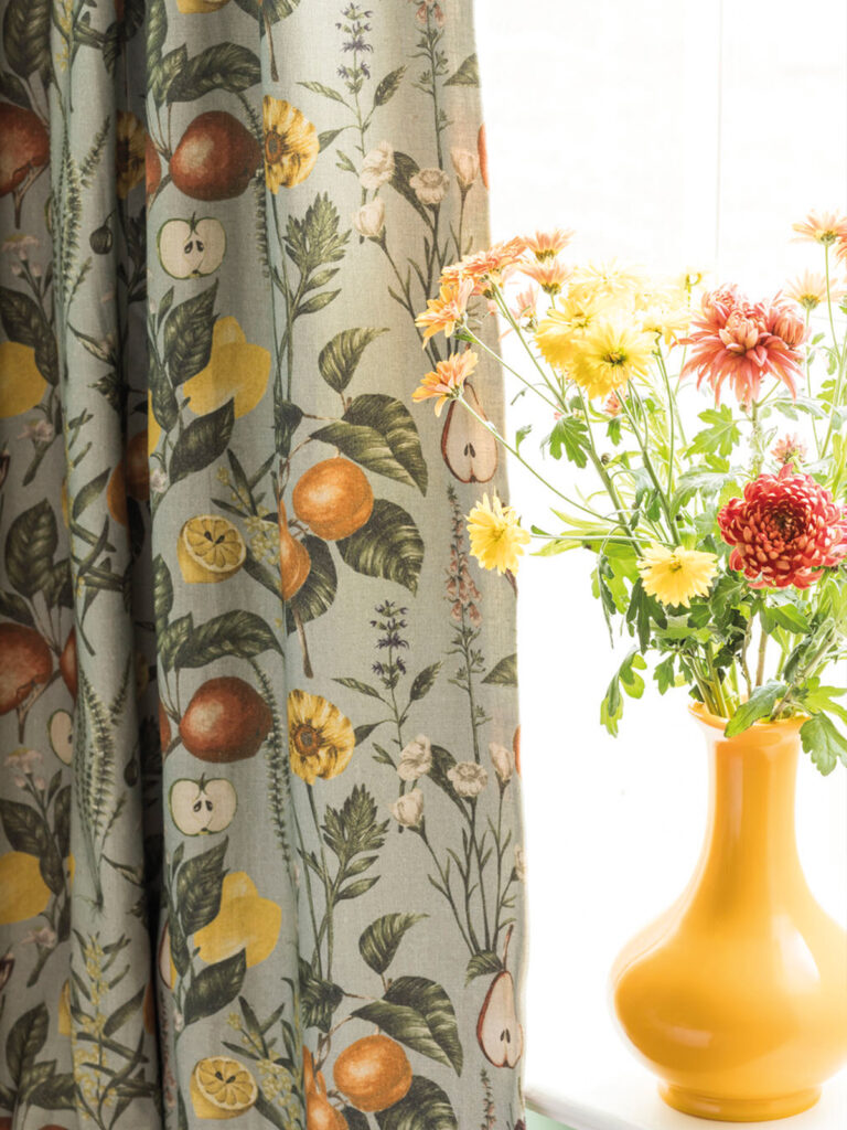close up image of fruit styled curtains next to flowers and window 