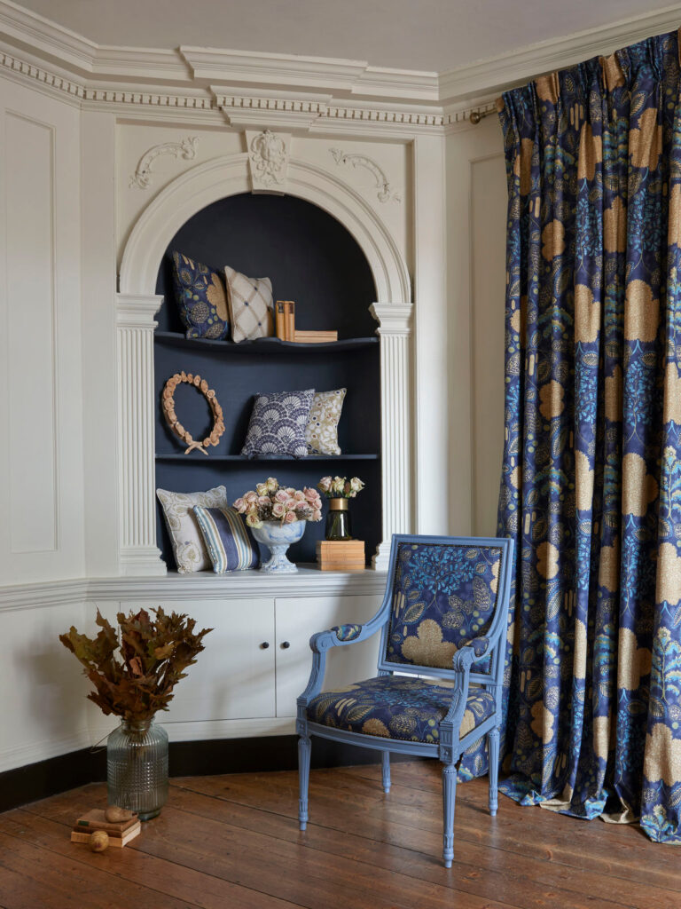 photo of blue chair next to blue and gold curtain 