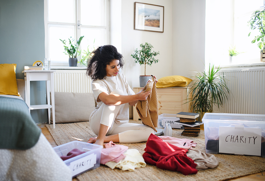 image of lady sitting in living room sorted through clothes for charity 