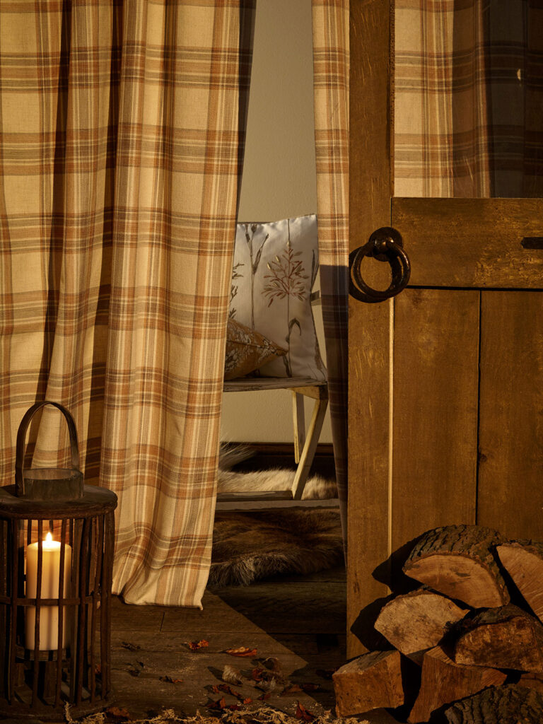 close up photo of yellow tartan curtains next to candle 