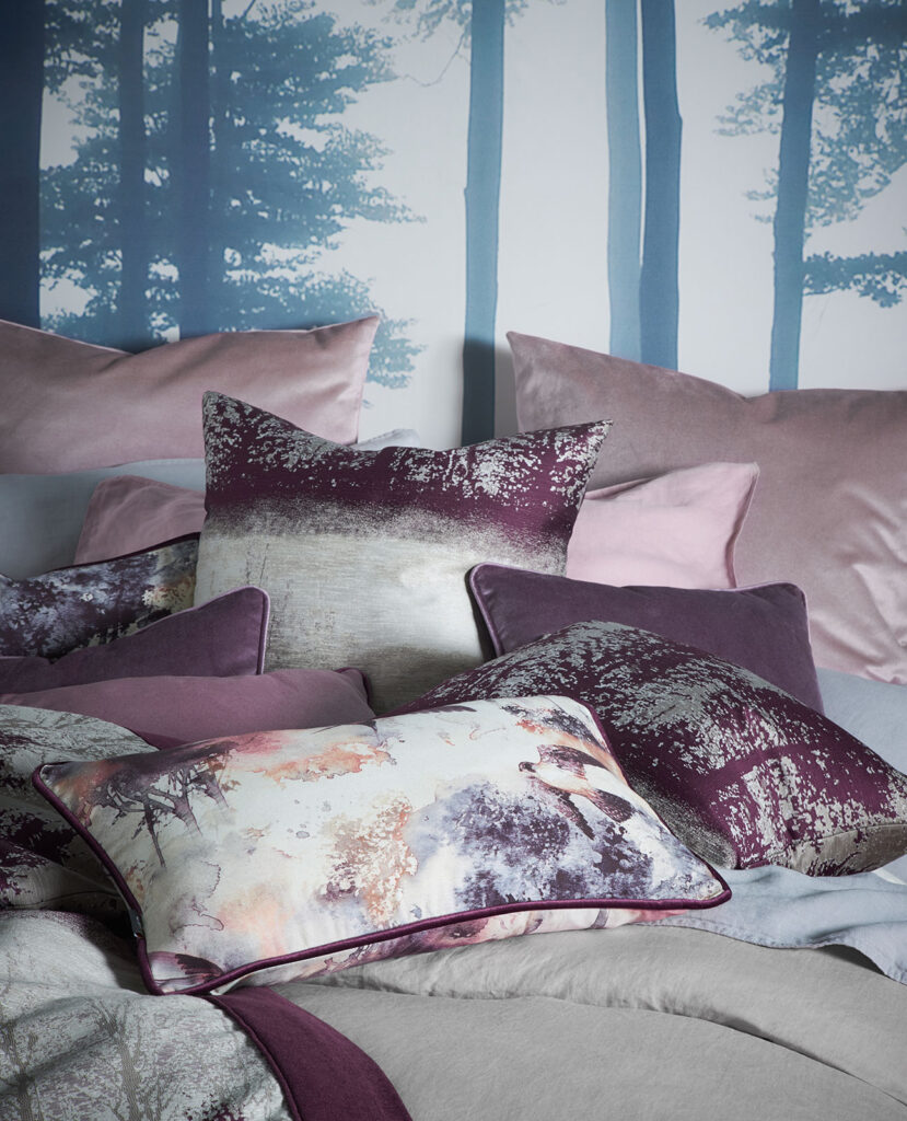 a phot of pick and aubergine coloured cushions on a bed