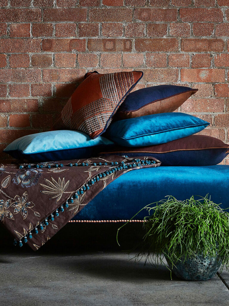 photo of cushions piled up on a blue and brown cocooned sofa