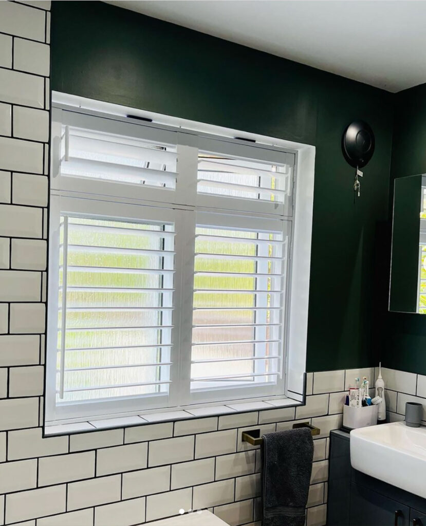 photo of a green and white bathroom with white blinds