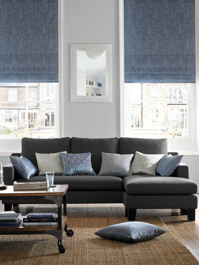 photo of a sofa in a living room in front of two big windows with tranquil blue blinds 
