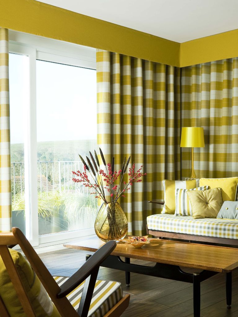 A yellow themed living room with bold patterns and checks