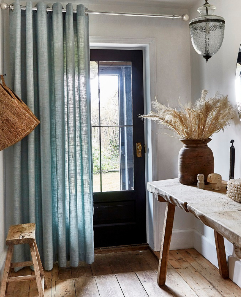 Linen curtains covering the front door of a chic cottage. 