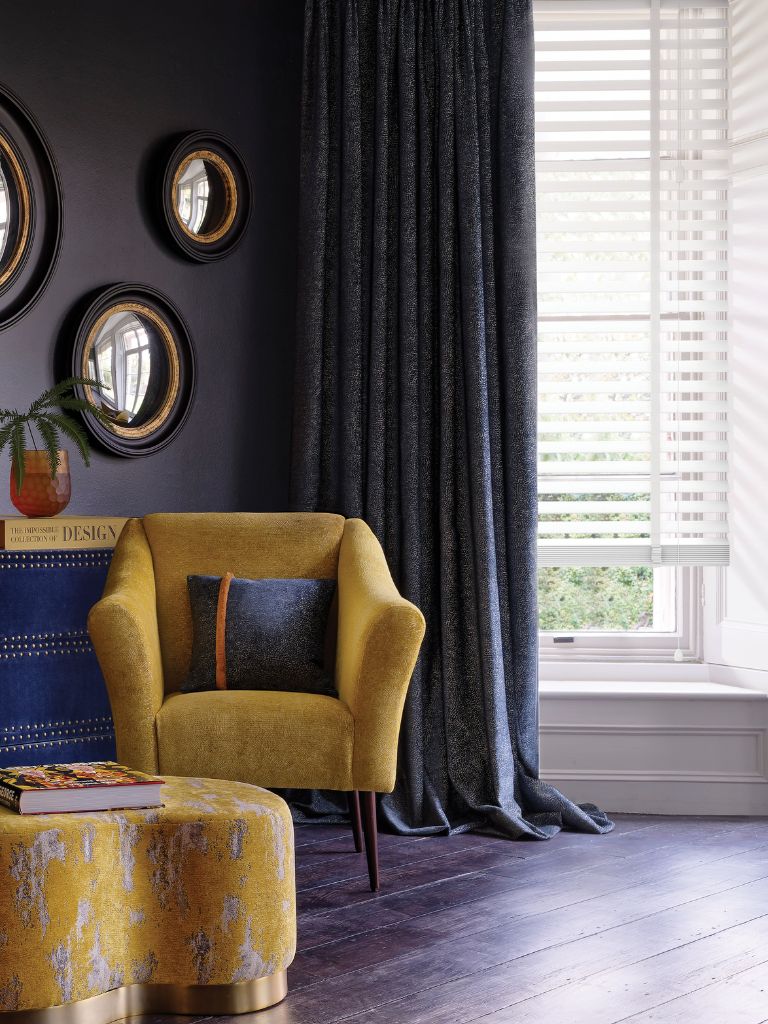 A beautiful purple living room with a yellow arm chair and foot stool.