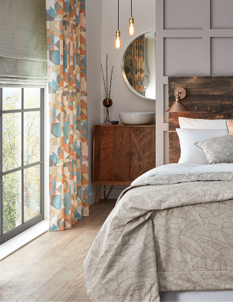 A chic bedroom featuring an orange and blue patterned curtain. 