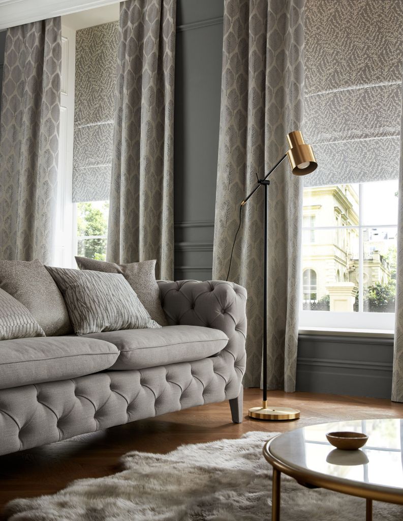 Blackout Roman blinds and curtains in a luxurious grey living room. 